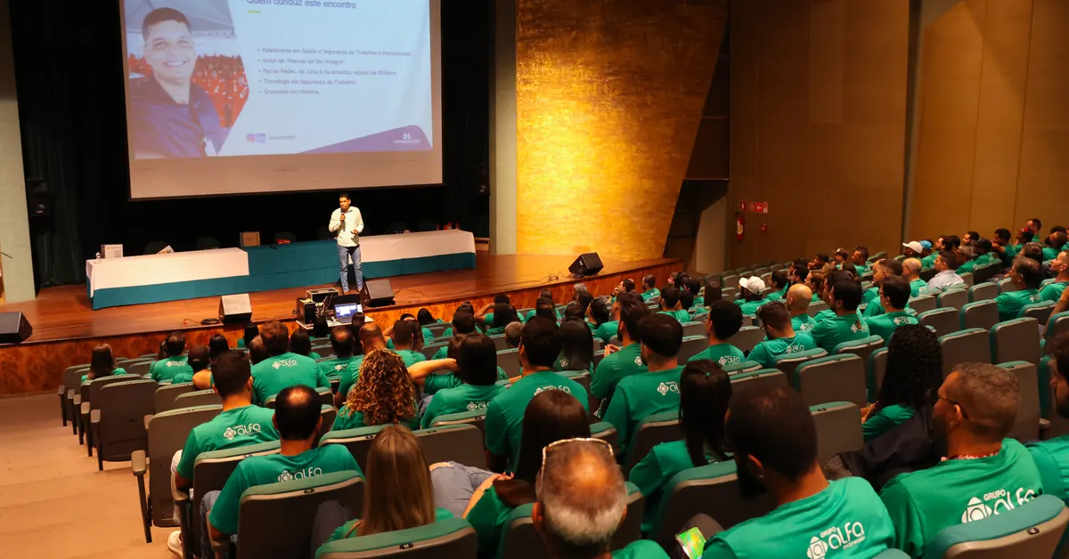 Palestra de segurança em auditório lotado, com a plateia acompanhando a apresentação no palco.