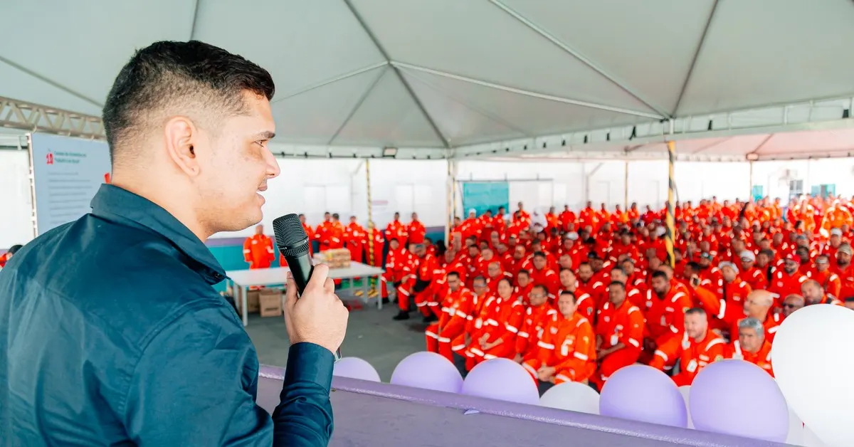 Palestrante de segurança do trabalho diante da plateia numa empresa, falando sobre gestão de riscos e prevenção de acidentes.