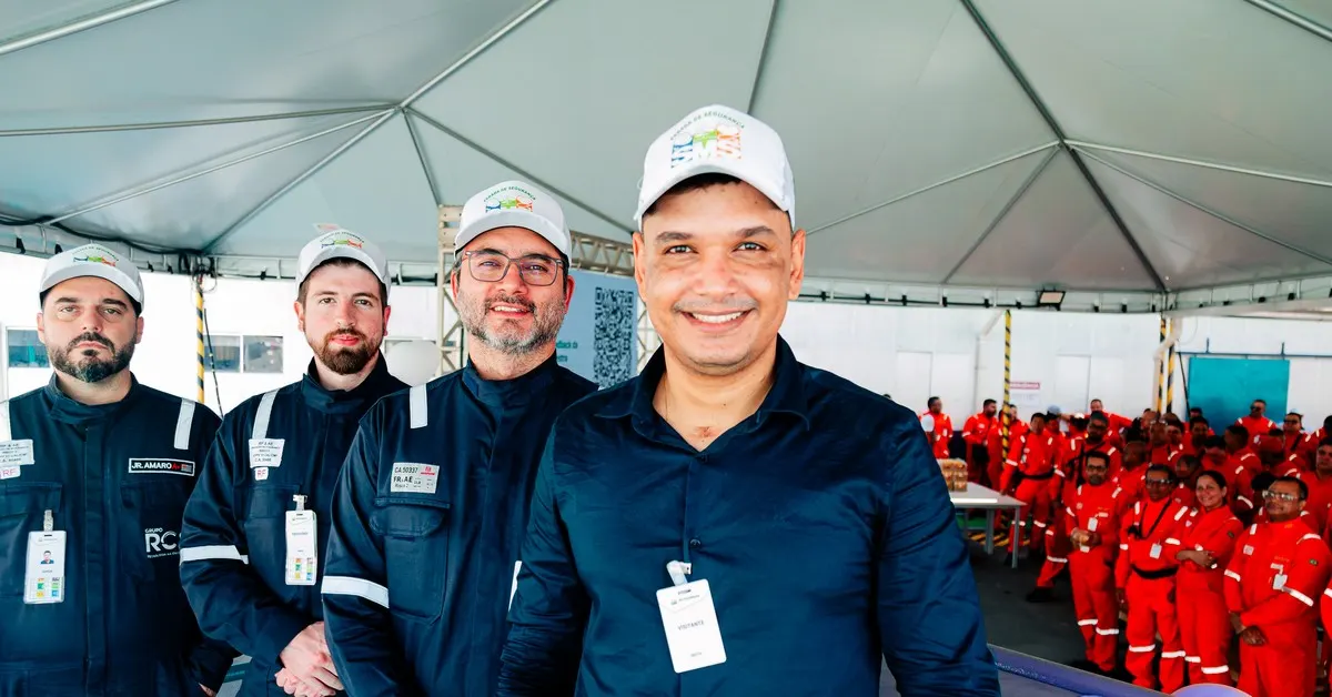 Palestrante de segurança do trabalho conversando de perto com uma equipe de trabalhadores reunida.