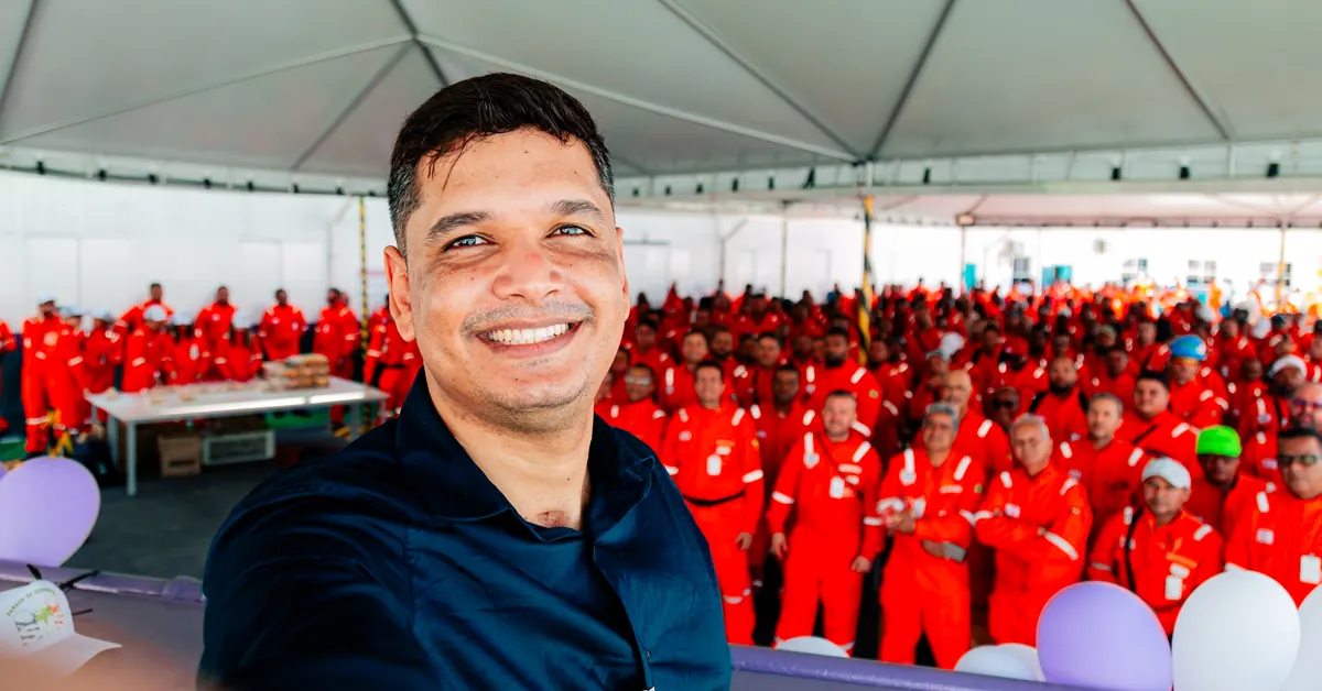Palestrante de segurança do trabalho sorrindo de frente para a plateia num momento leve da conversa.