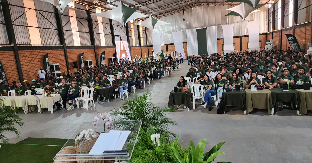 Centenas de trabalhadores reunidos em galpão durante um evento de SIPAT.