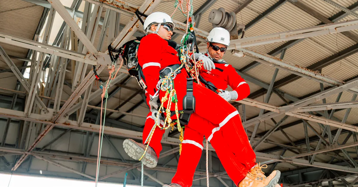 Profissionais em treinamento prático de segurança com cordas e equipamentos de proteção, exercício de prevenção de acidentes de trabalho.